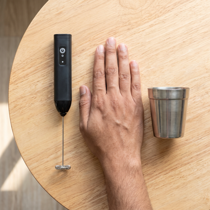 Milk frother size compared with a chai glass and hand